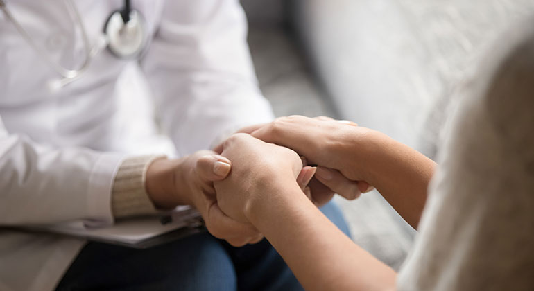 Image of a doctor holding a person's hands in a caring way